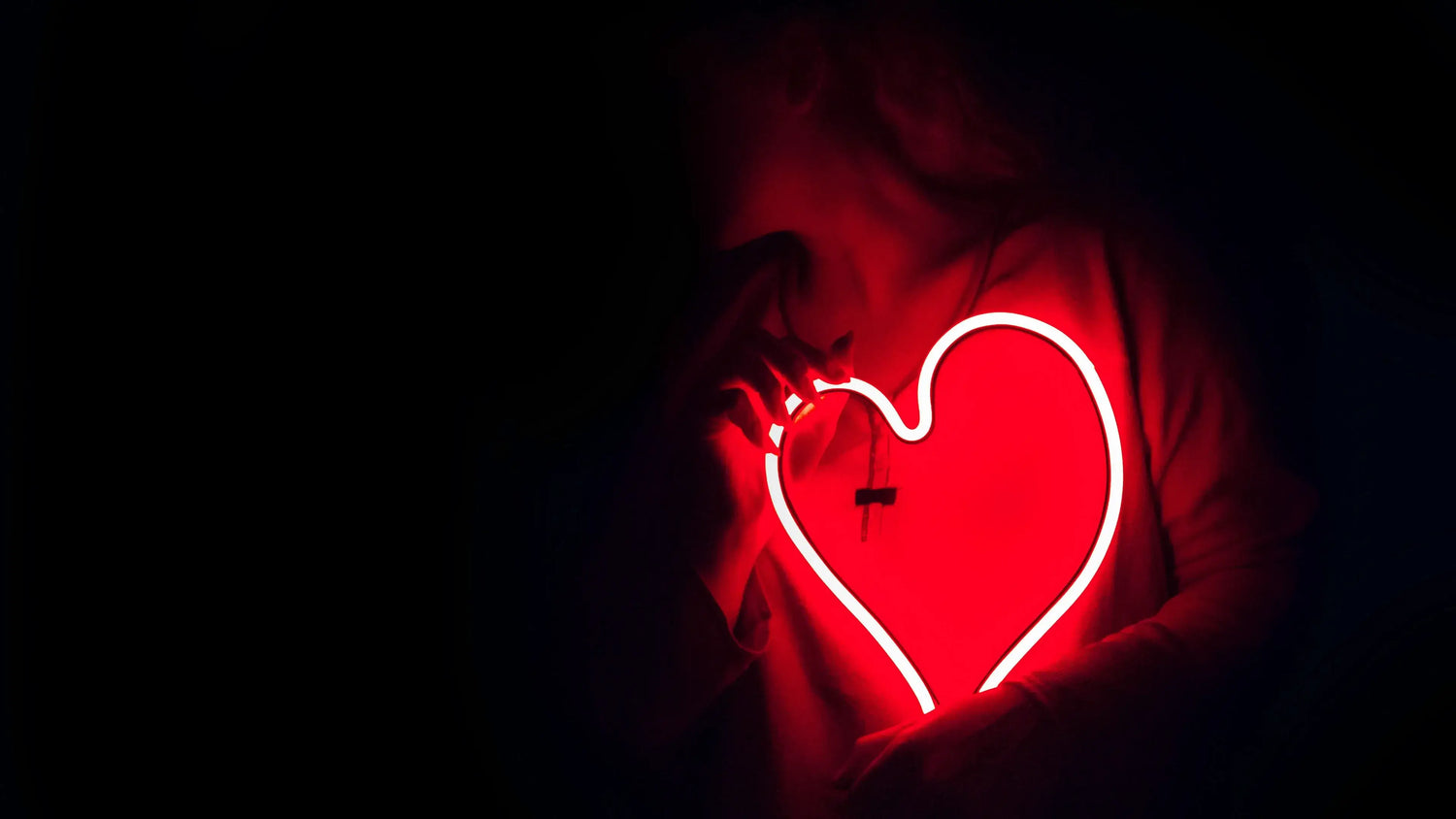 woman holding a heart neon