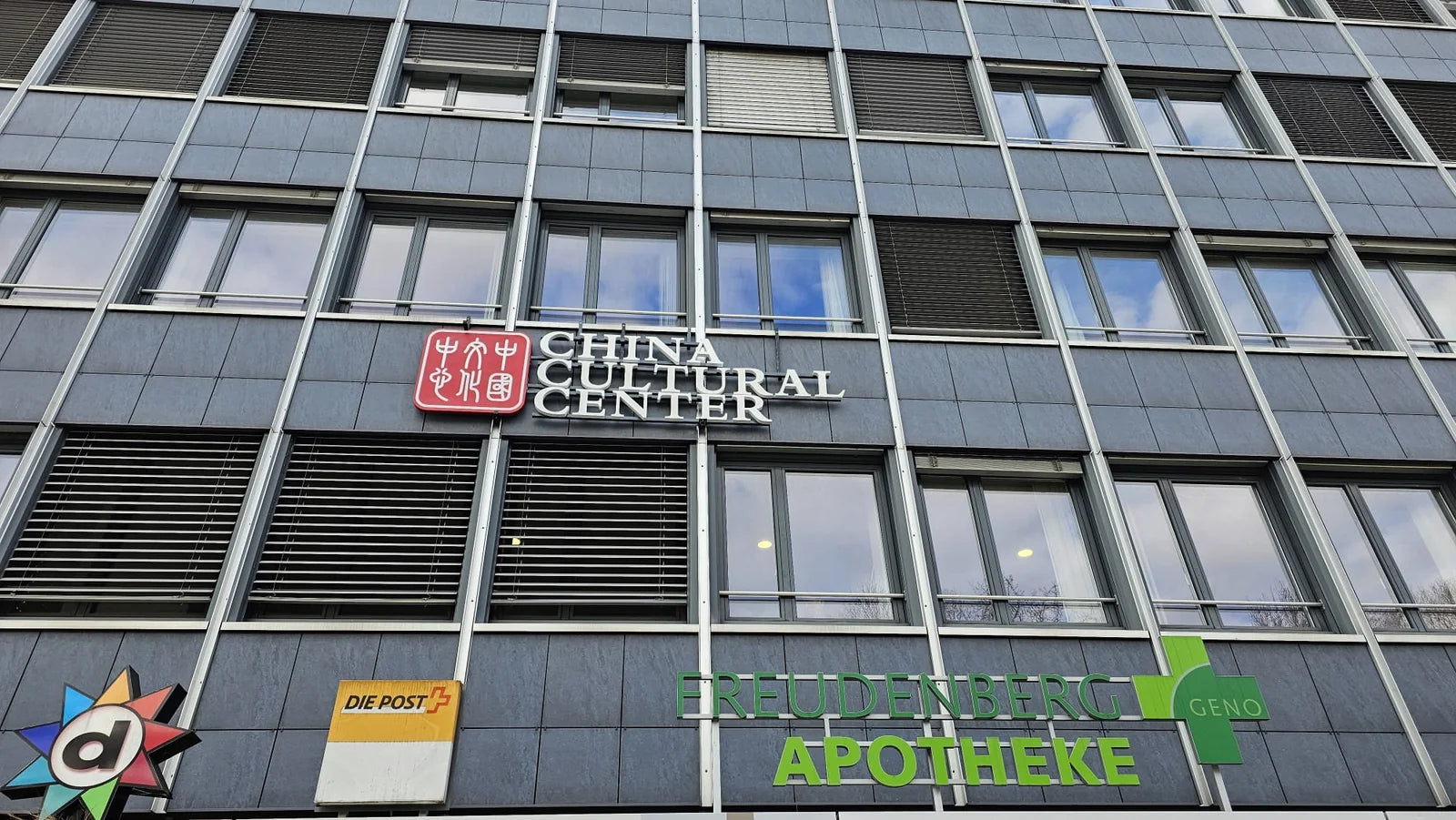 Fassade des Einkaufszentrums Freudenberg in Bern mit der neuen Leuchtreklame des China Cultural Center aus einem roten Logo und weissen Buchstaben.