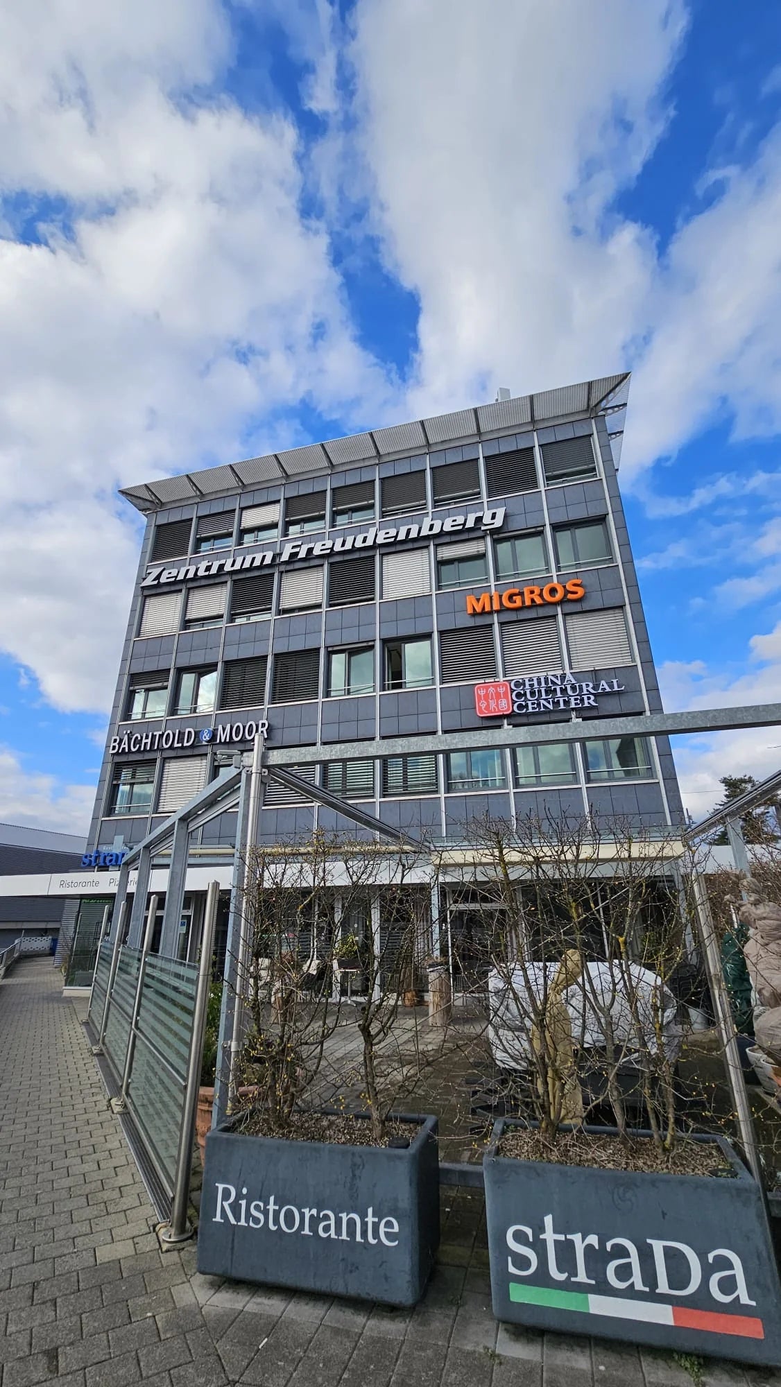 Gesamtansicht des Einkaufszentrums Freudenberg in Bern mit der installierten Leuchtreklame des China Cultural Center an der Fassade.