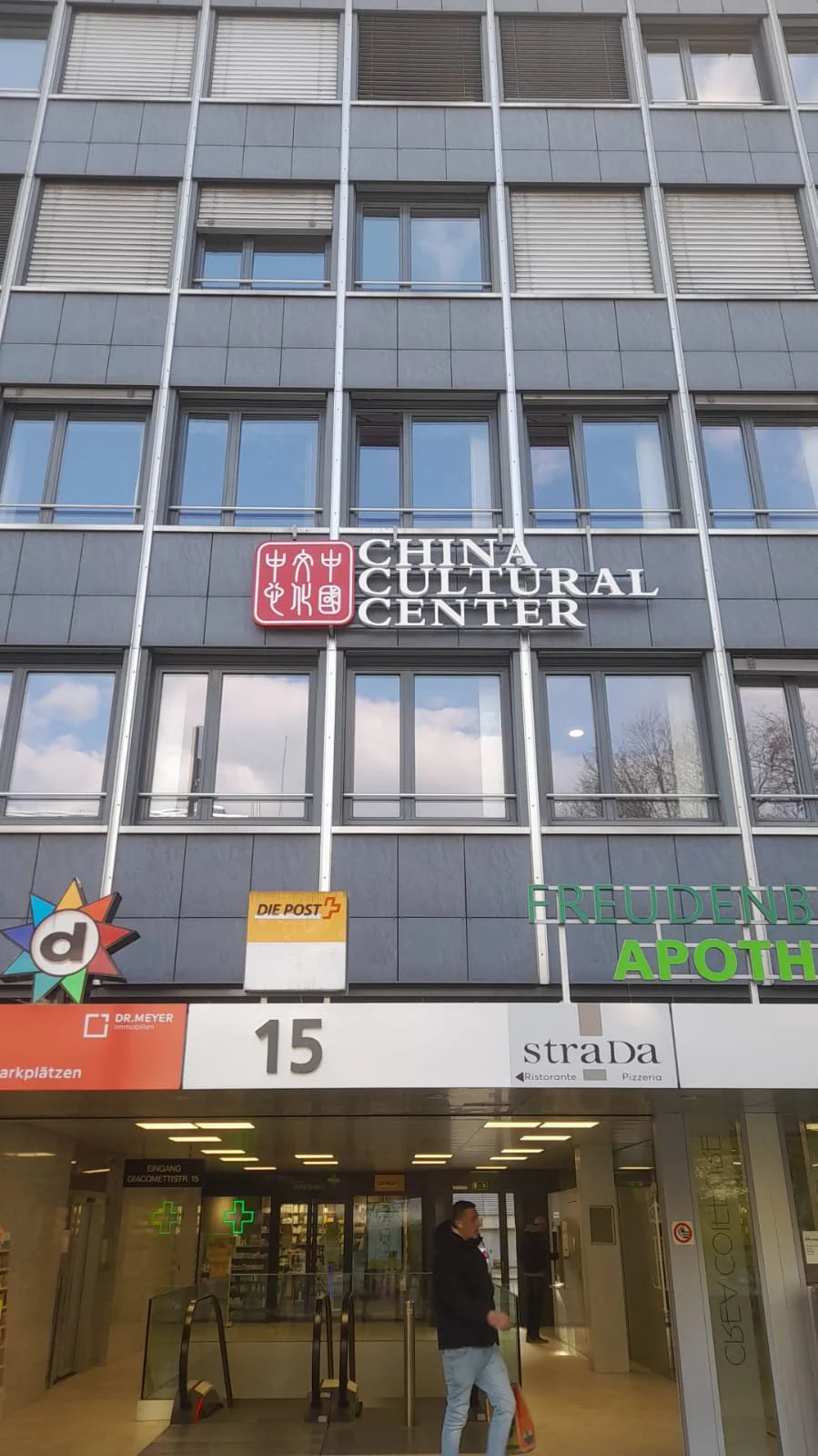 Neue Leuchtreklame des China Cultural Center mit rotem Logo und weissen Buchstaben an der Fassade des Einkaufszentrums Freudenberg in Bern.