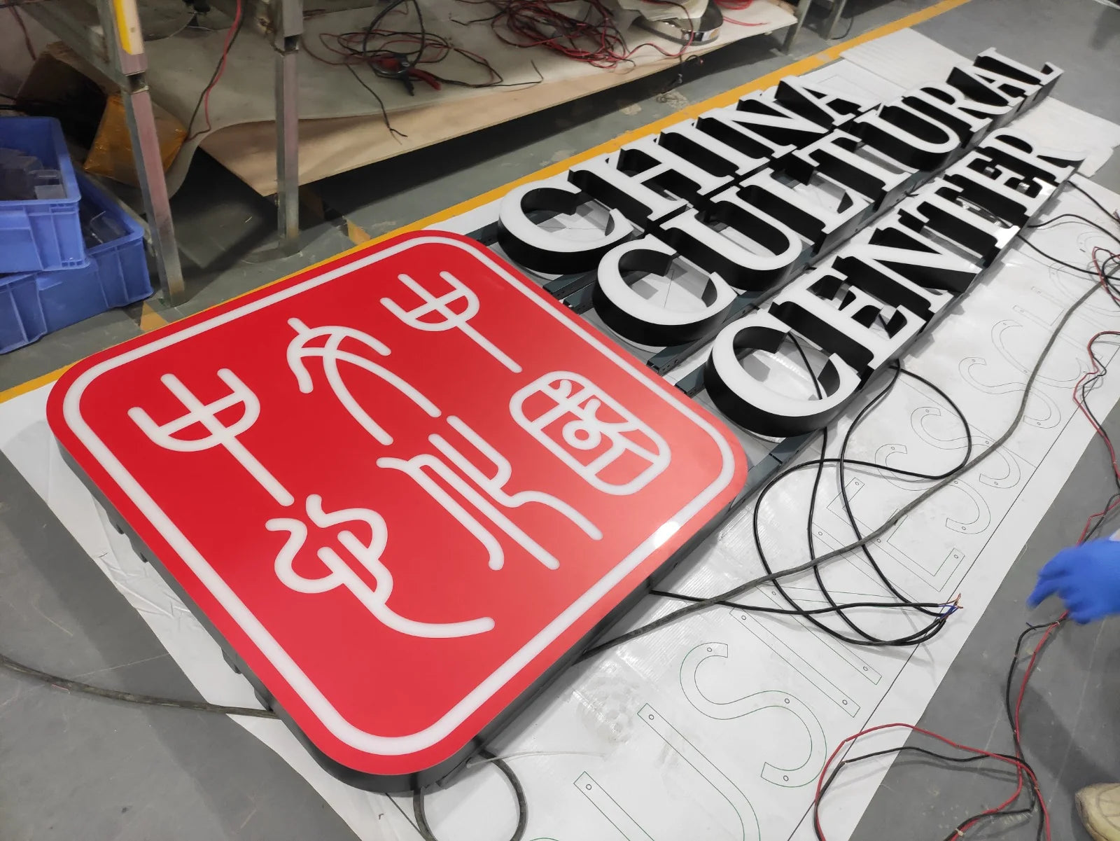 Rotes Logo des China Cultural Center mit weissen Zeichen, in der Werkstatt neben dem Schriftzug zusammengestellt.