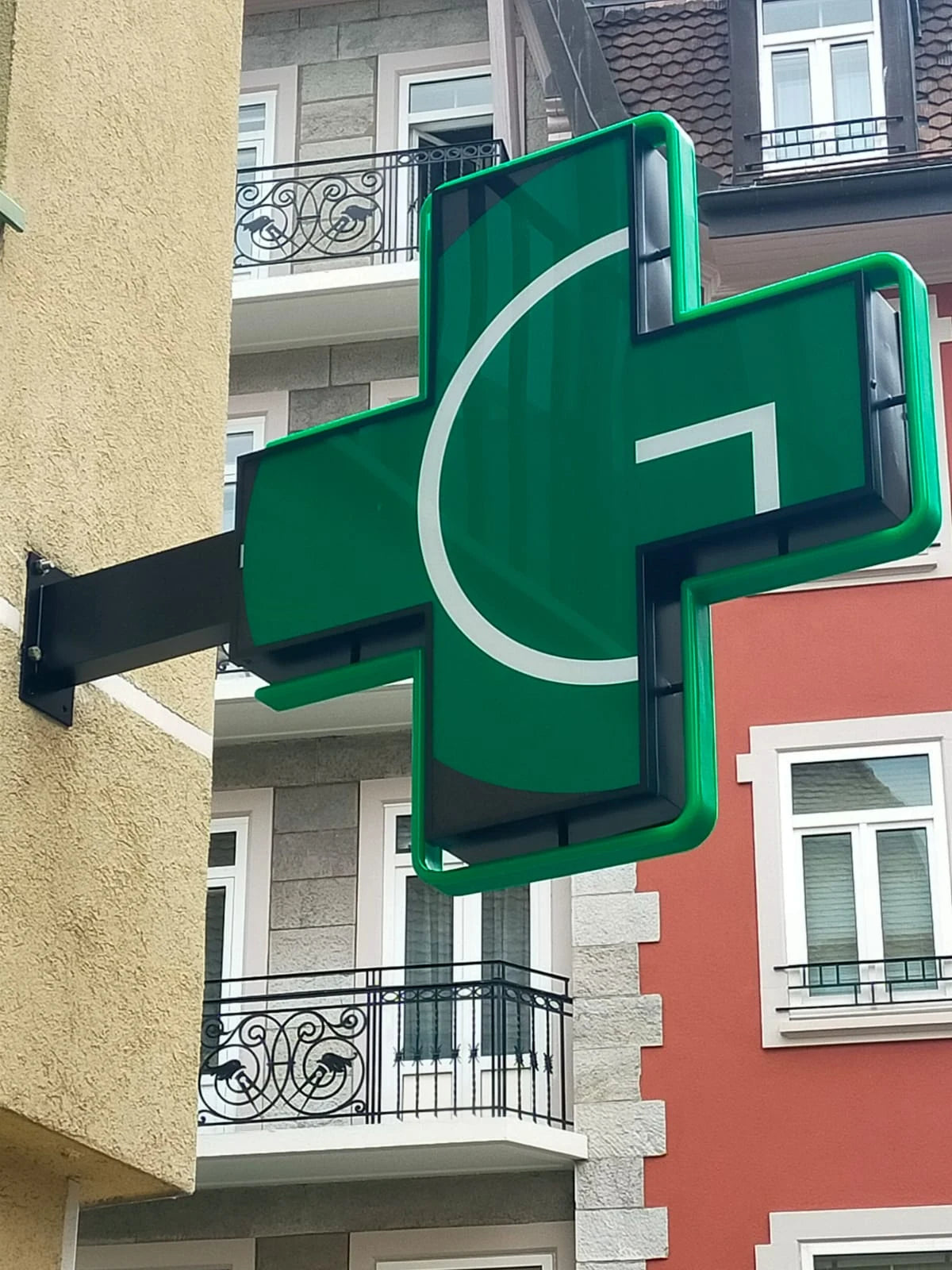 Andere Seite des montierten grünen Apothekenkreuzes in Clarens mit grüner Kontur und weissem Motiv.