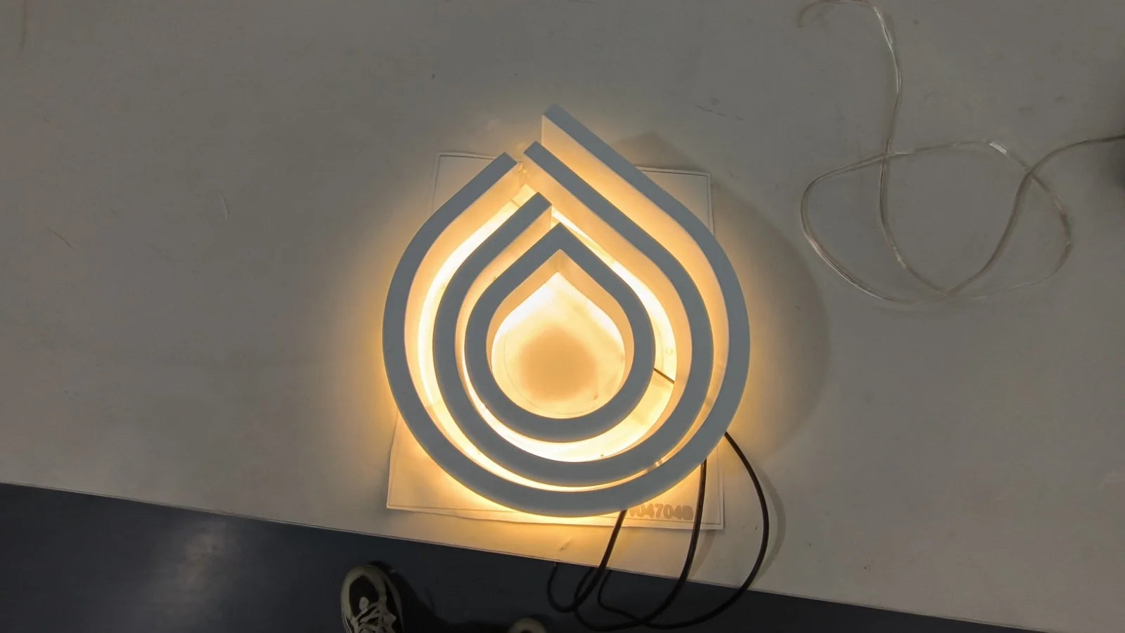 Eingeschaltetes Lavanderia-Logo in der Werkstatt mit warmem Lichtkranz hinter der weissen Front.