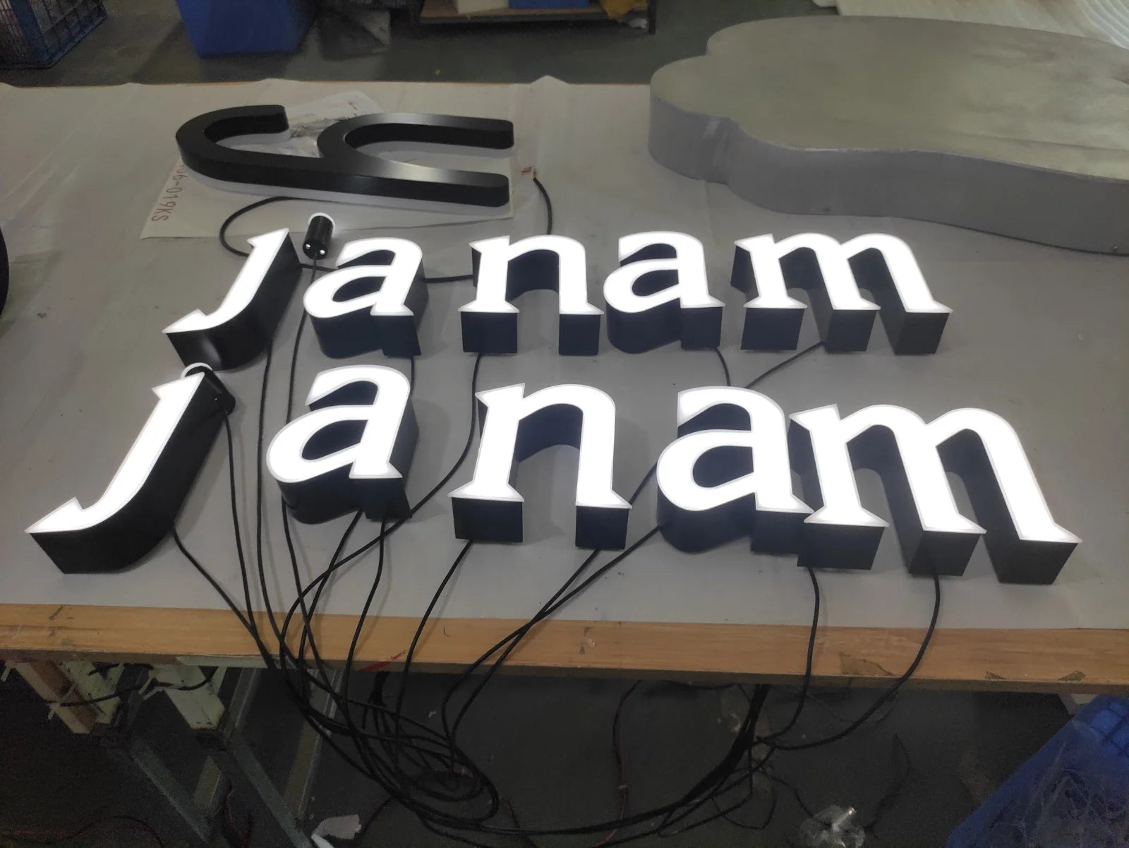 Two sets of illuminated janam letters on a workshop table before installation.