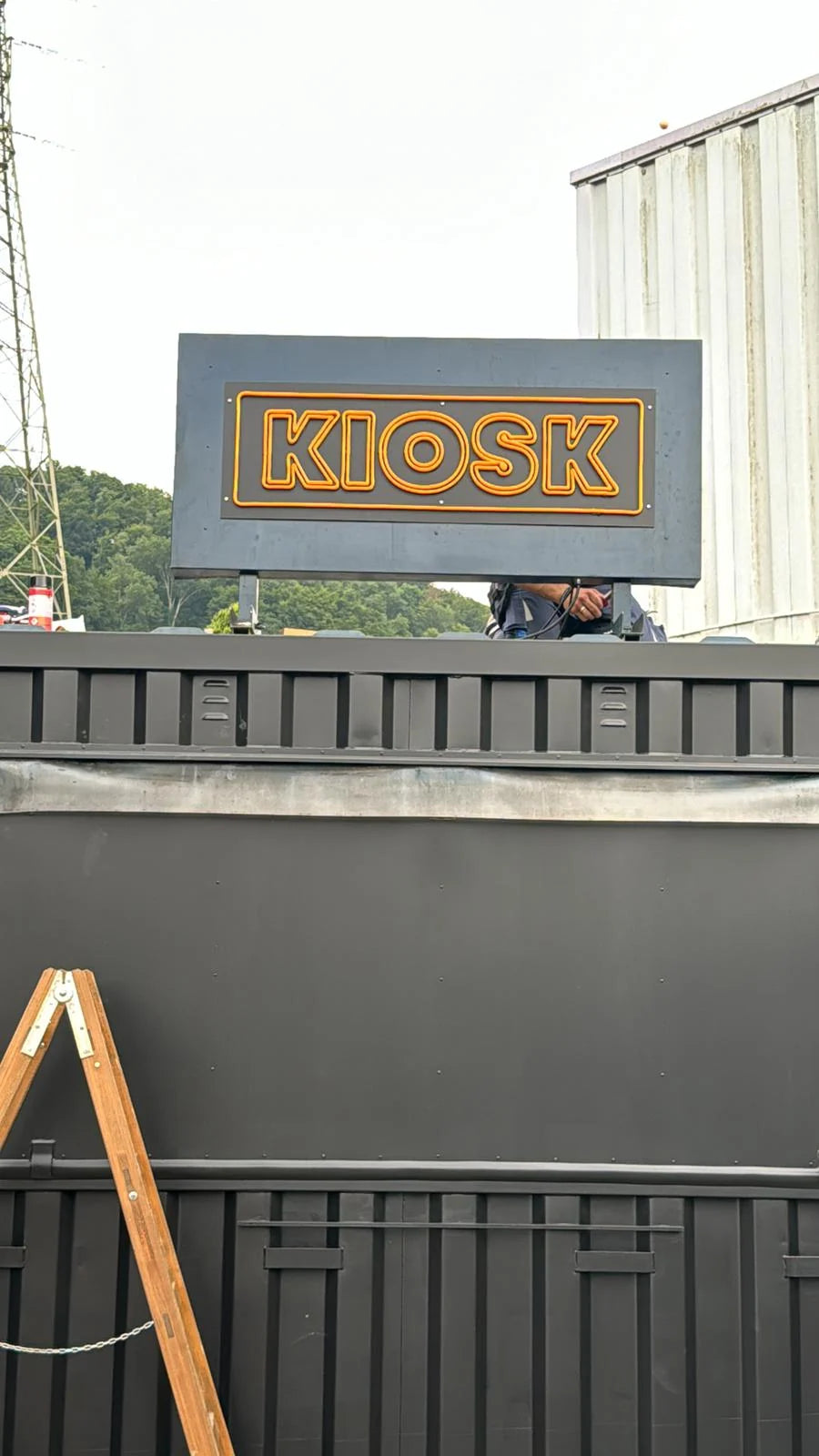 Orangefarbenes LED-Neonschild KIOSK auf einer dunklen Konstruktion während der Montage für das Montreux Jazz Festival in Montreux.