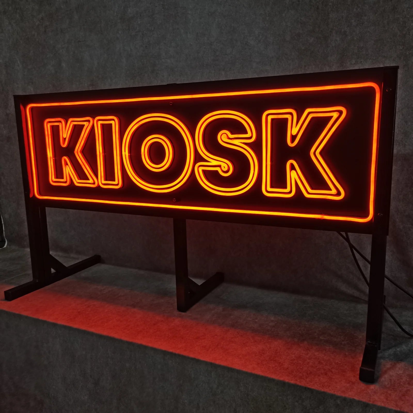 Schrägansicht des eingeschalteten KIOSK-Schilds auf seiner Stützkonstruktion in der Werkstatt.
