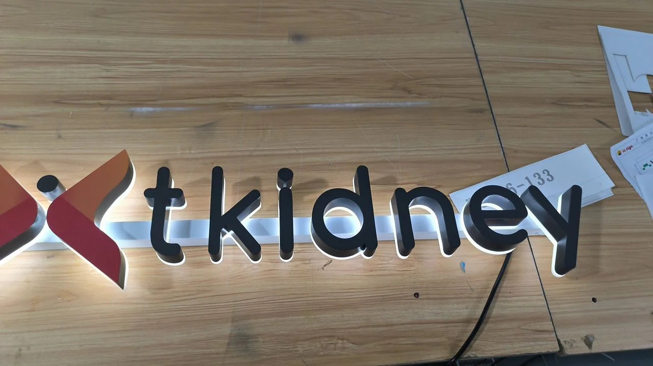 Raised black Nextkidney letters during workshop lighting tests, with the halo visible behind the lettering.