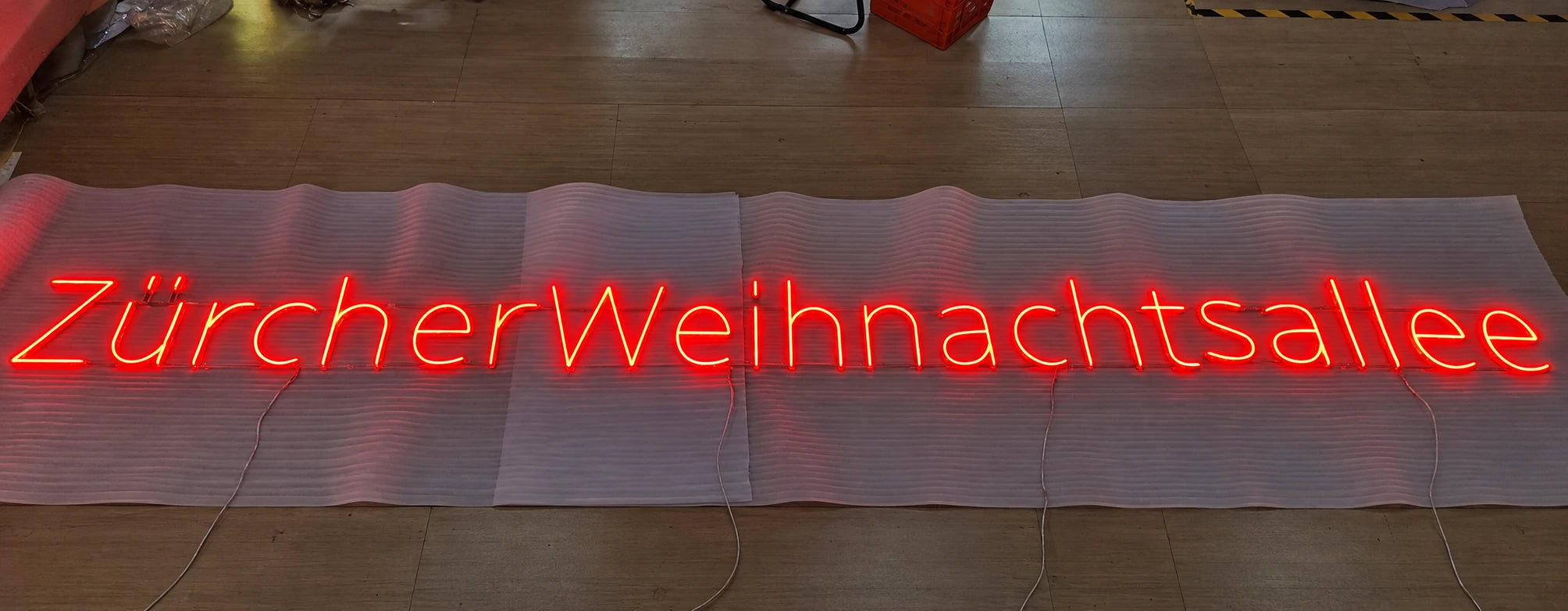 Handmade red Zürcher Weihnachtsallee neon illuminated during workshop checks.